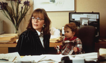 Diane Keaton with a baby in a chair next to her.