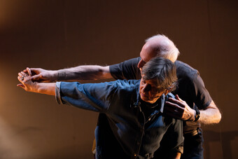 A man guides a woman's arm during a performance.
