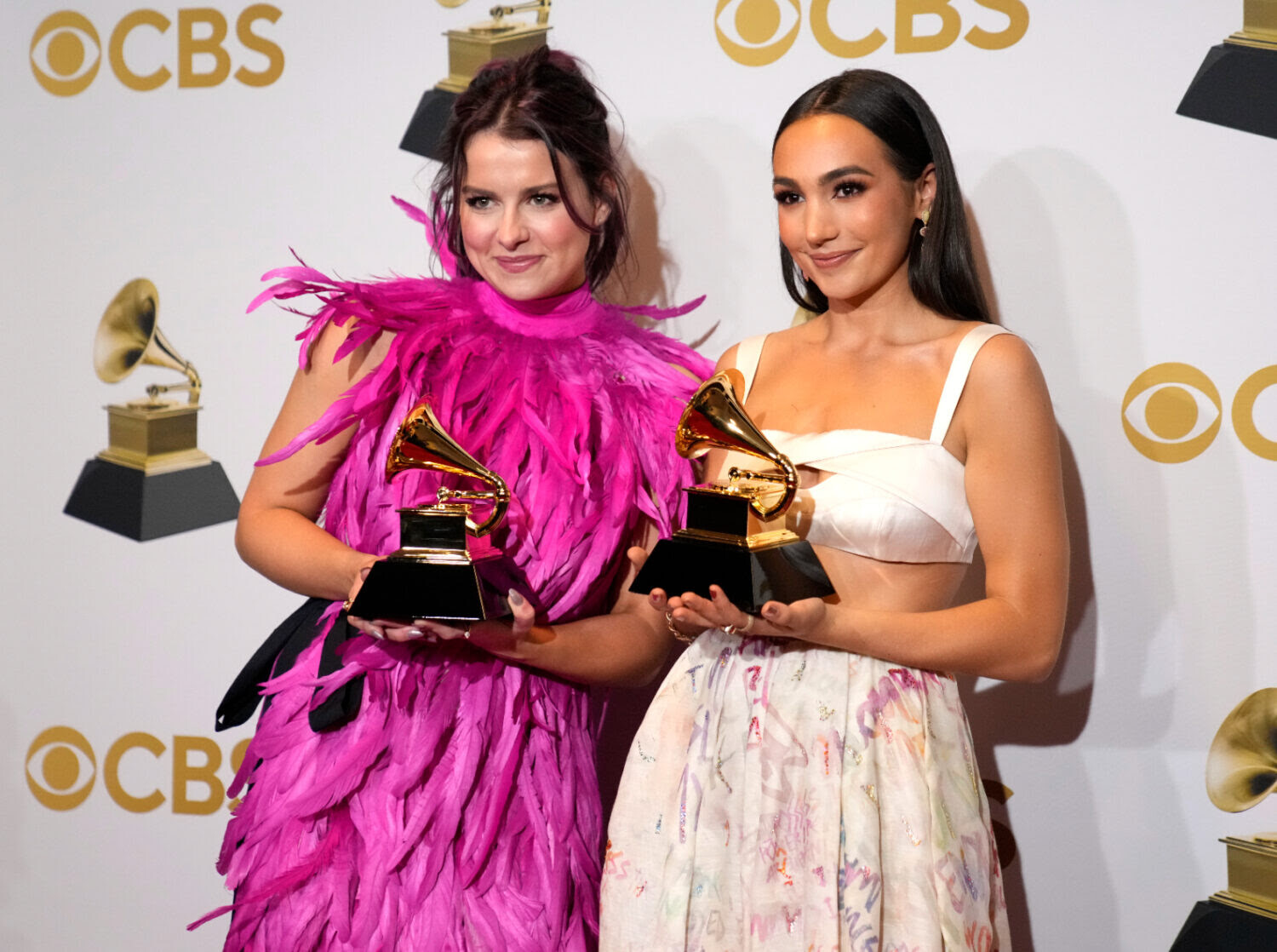 Two women posing for a picture, each holding a Grammy.