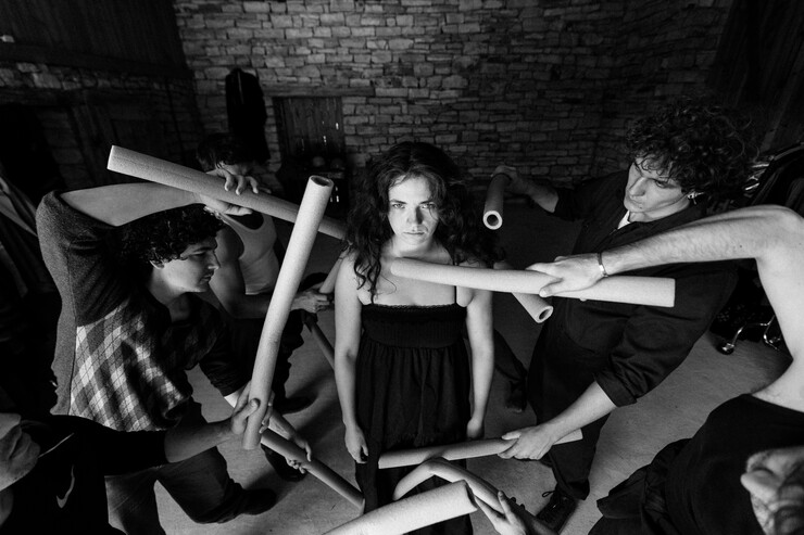 A woman surrounded by people stares at the camera.