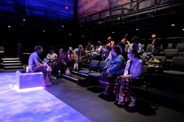A director speaks to a group of students in a theatre.