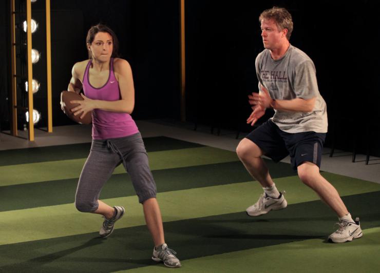 Two actors practice playing football.