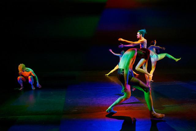 five performers dance in colored light