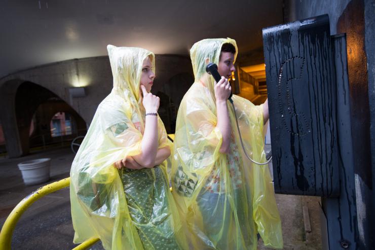 two people in raincoats at a pay phone
