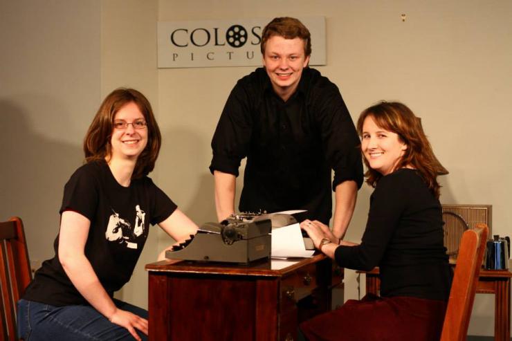 three people posing with a typewriter