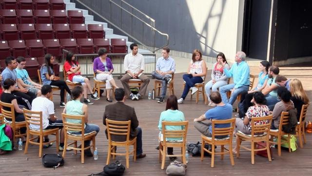 People sitting in a circle talking on an outdoor stage