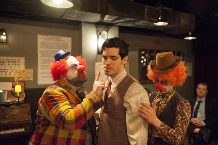 Two clown performers stand in front and behind a third non-clown performer.
