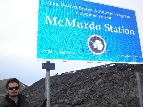 Mat Smart poses next to the welcome sign for McMurdo Station, Antarctica.