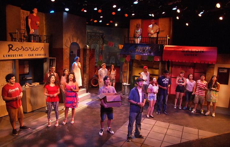 Performers in In the Heights sing while on a set that resembles a New York City street.