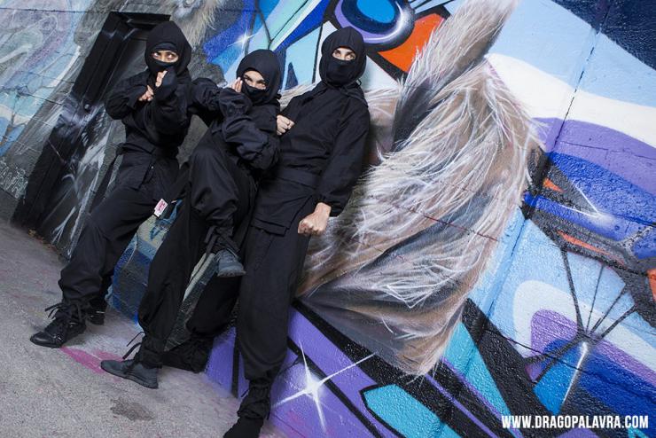 three performers in ninja costumes pose