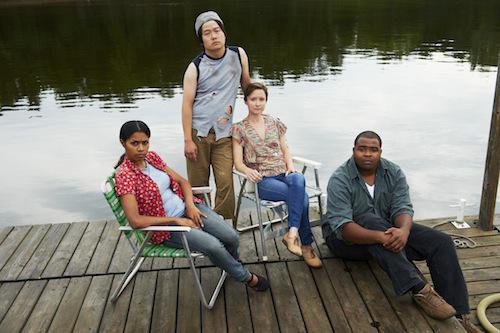 Four actors sit on a dock.