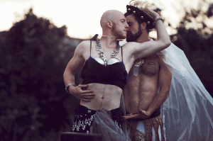 Two performers embrace each other outside.