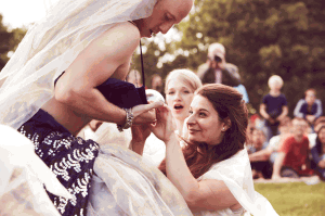 A cast member wearing a bridal veil interacts with an audience member.