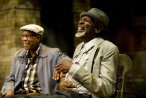 Two Black actors laughing in a scene.