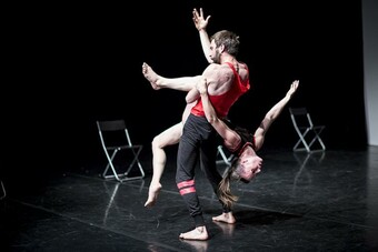 Two people holding each other in acrobatic dance. 