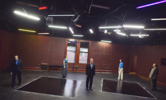 Five people stand on a stage with two large black squares on the floor.