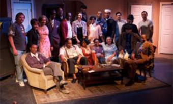 The cast and crew of a play gathered around their set.