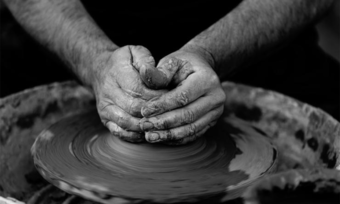 Hands making pottery out of clay.