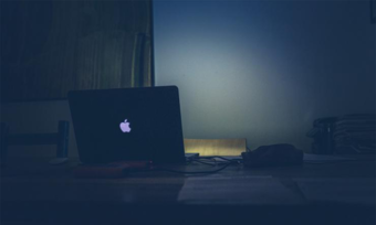 A laptop sits on a table in the dark.