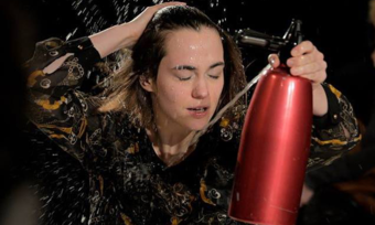 woman performer spraying herself with a seltzer can.