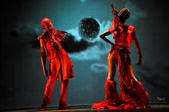 two performers in red costumes with a backdrop of the moon.