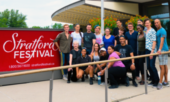 multiple people posing for a photo next to the stratford festival sign
