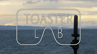 Toaster Lab logo overlaid a camera on a tripod by water.