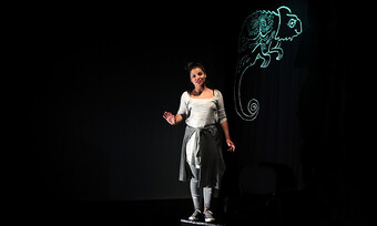 actor on stage with chameleon outline in background