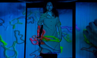 performer on stage, projections of squiggles cover them.