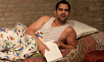 person in a bed, holding a book.