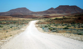 a desert road leading toward mountains