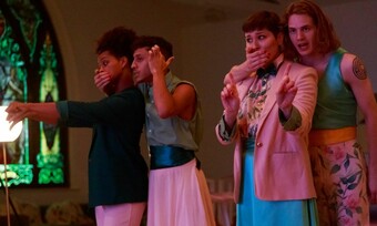 Two actors, standing behind two other actors, with one hand on their mouths. The actors with their mouths covered have both arms out.