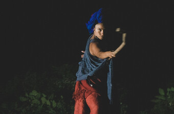 A person wearing blue and red holding out a stick.