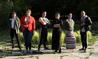 six performers standing in a park.