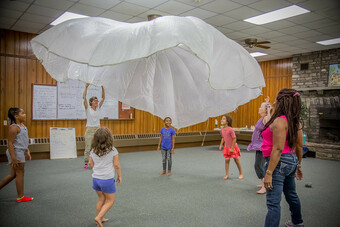 Children throwing a parachute in the air.