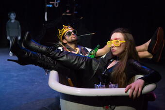 Two actors in sunglasses lounge together in a bathtub. 
