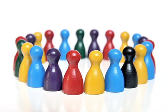 Many multi-colored board game pawns arranged in a circle.