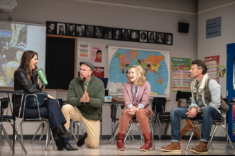 Four actors sit in a classroom set.