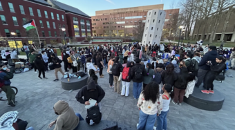 A group of students protest on a schools campus, with a Palestinian flag