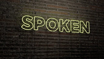 neon sign spelling out SPOKEN in front of a brick wall.