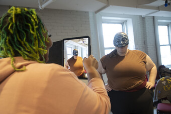 A person in a commedia dell'arte mask poses for a photo.