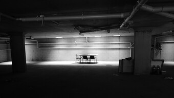 folding chairs around a table in a dimly lit warehouse.