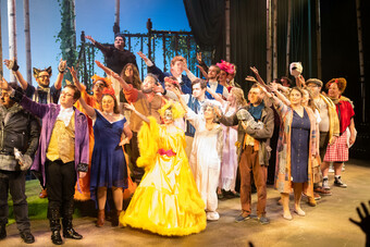 A group of people are gathered on stage wearing costumes.