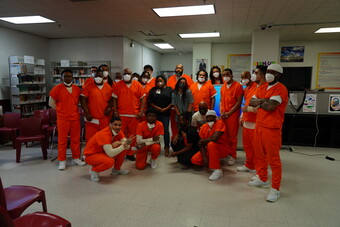  Members and participants of Spit Dat Academy at the District of Columbia Central Detention Facility wearing orange jumpsuits pose for a photo.