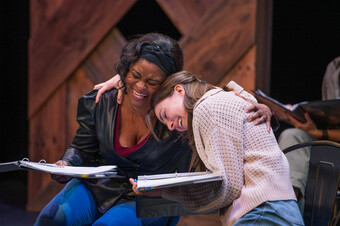 Two people embrace happily on stage. 