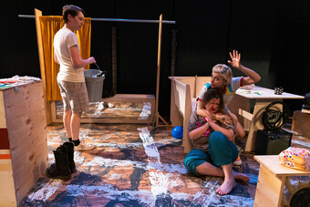 A group of people on stage surrounded by a wooden set. 