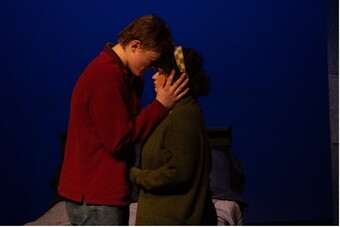 Two people stand in front of each other with their foreheads touching.