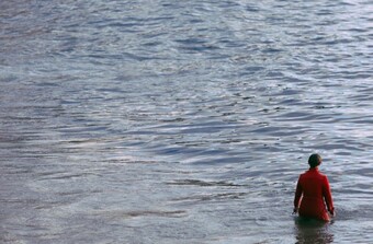 A person dressed in red standing in a body of water. 