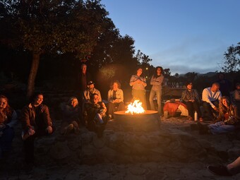 A group of people sitting around a campfire.