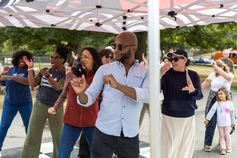 A group of people dancing under a tent outside.
